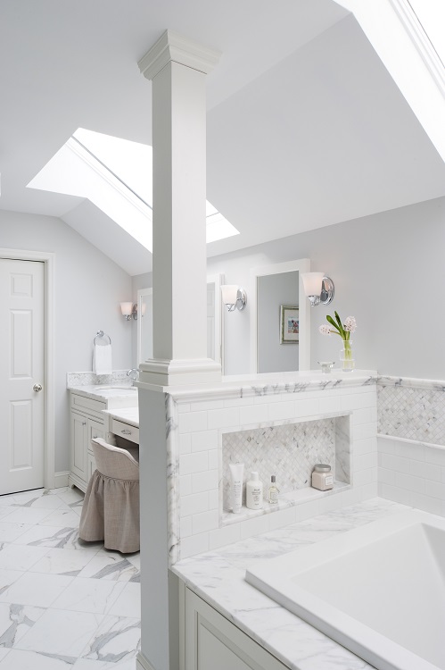 Villanova primary bath soaking tub with marble tiled niche, marble tile surround, and half wall 