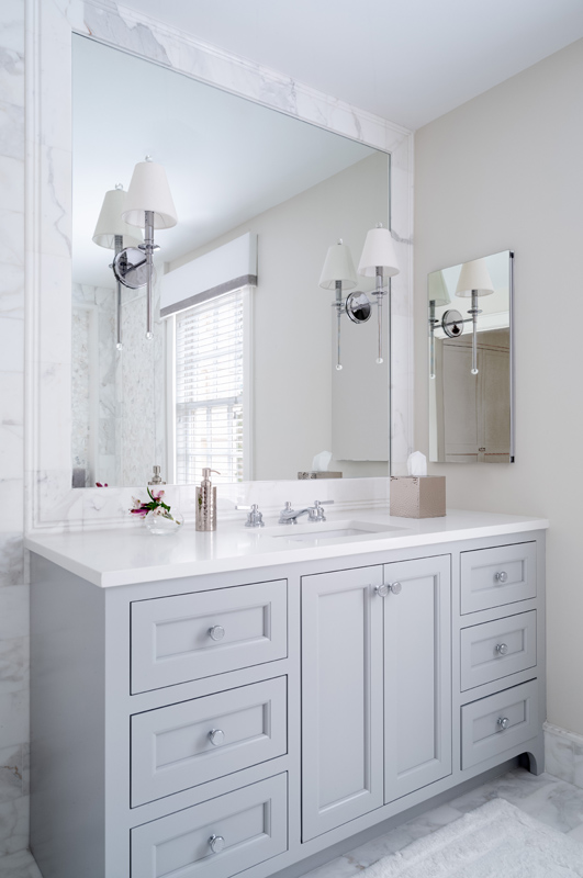 Custom painted gray vanity with a large mirror and wall sconces by Glenna Stone Interior Design