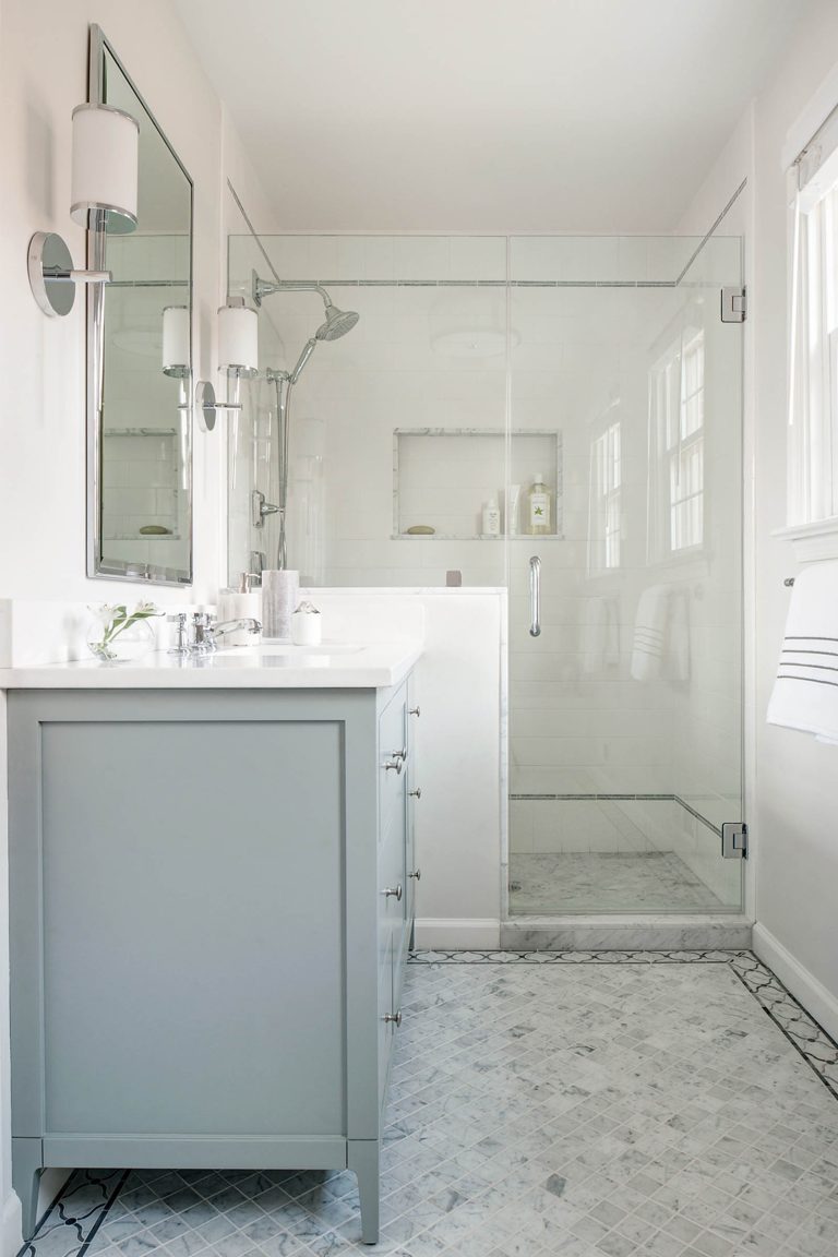 Bright, modern bathroom located in Lafayette Hill, featuring a glass shower enclosure, white walls, and a light gray vanity with marble countertop—designed by interior designer Glenna Stone for both style and function.