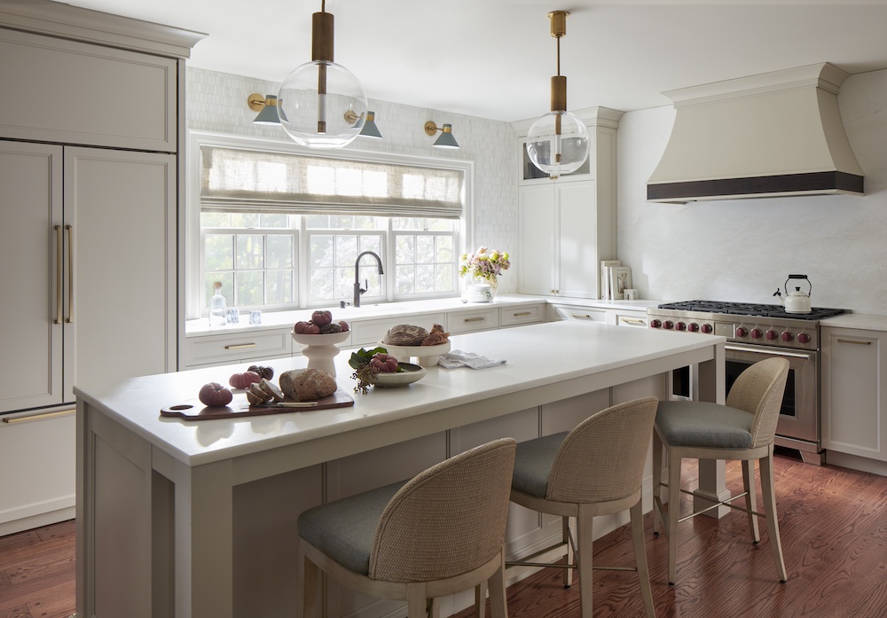 Luxury kitchen design with a large white island, custom cabinetry, pendant lights, and appliances.